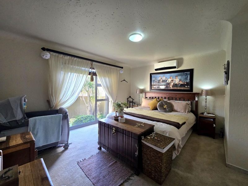 Spacious bedroom featuring carpeted flooring, a split-system air conditioner, and a large sliding glass door providing access to the outdoor area.