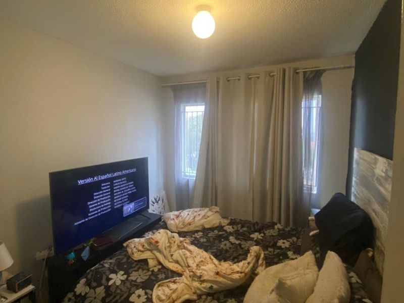 A functional bedroom featuring tiled flooring and windows equipped with security bars, providing a basic and practical living space.