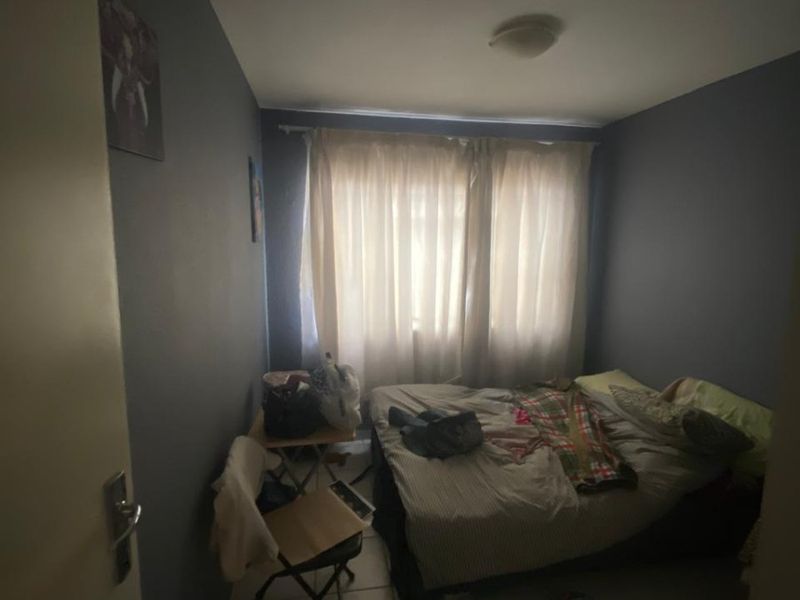 A standard bedroom featuring tiled flooring and neutral wall paint, offering a functional space with natural light through the window.