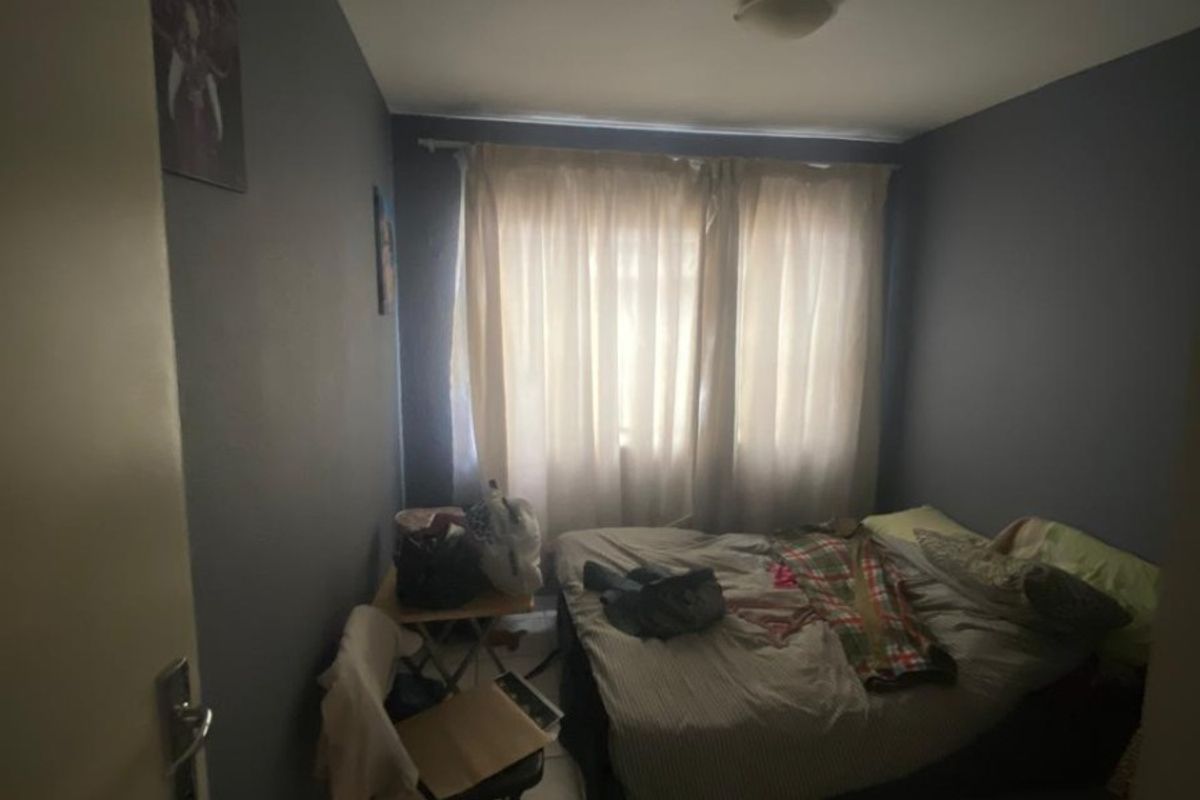 A standard bedroom featuring tiled flooring and neutral wall paint, offering a functional space with natural light through the window.