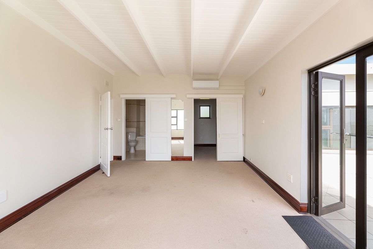 Spacious bedroom featuring exposed beam ceilings, split system air conditioning, and direct access to an outdoor area through sliding doors.
