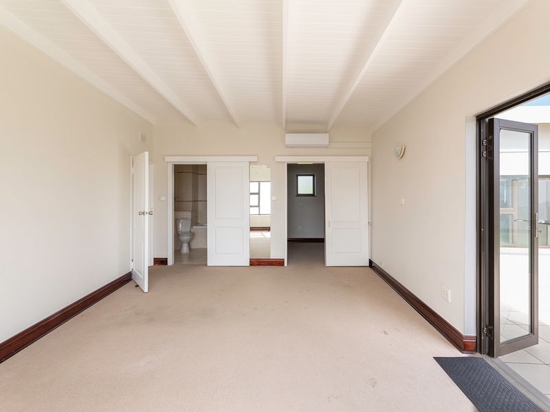 Spacious bedroom featuring exposed beam ceilings, split system air conditioning, and direct access to an outdoor area through sliding doors.