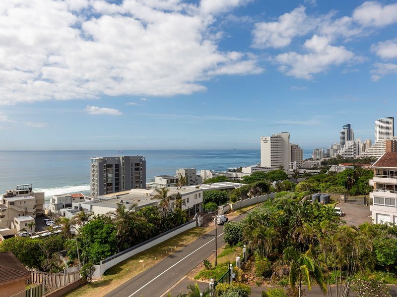 Elevated coastal view overlooking the surrounding urban landscape, lush greenery, and the ocean horizon.