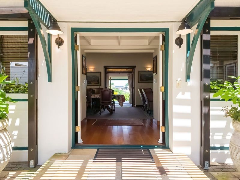 Inviting front entrance featuring a covered porch with decorative timber detailing, leading into a bright interior with polished timber flooring.