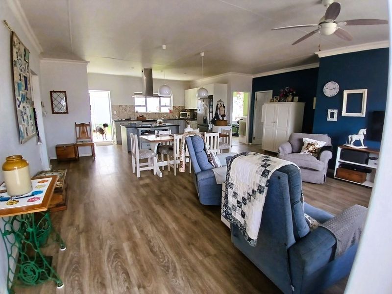 Spacious open-plan living and kitchen area featuring modern laminate flooring, a central kitchen island, and a ceiling fan, creating a functional family space.