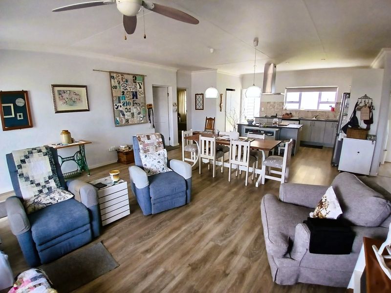 Spacious open-plan living, dining, and kitchen area featuring modern laminate flooring, a central kitchen island, and neutral finishes throughout.