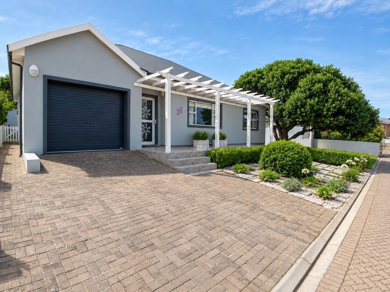 Well-maintained front facade featuring a paved driveway, single garage, and a charming pergola over the entrance steps.
