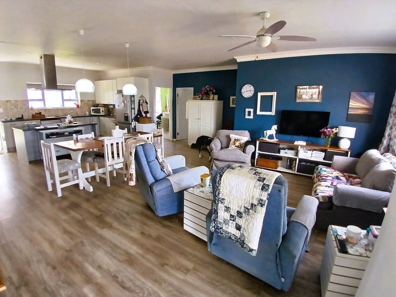 Spacious open-plan living area featuring a modern kitchen with an island, dining space, and a comfortable lounge area with laminate flooring throughout.