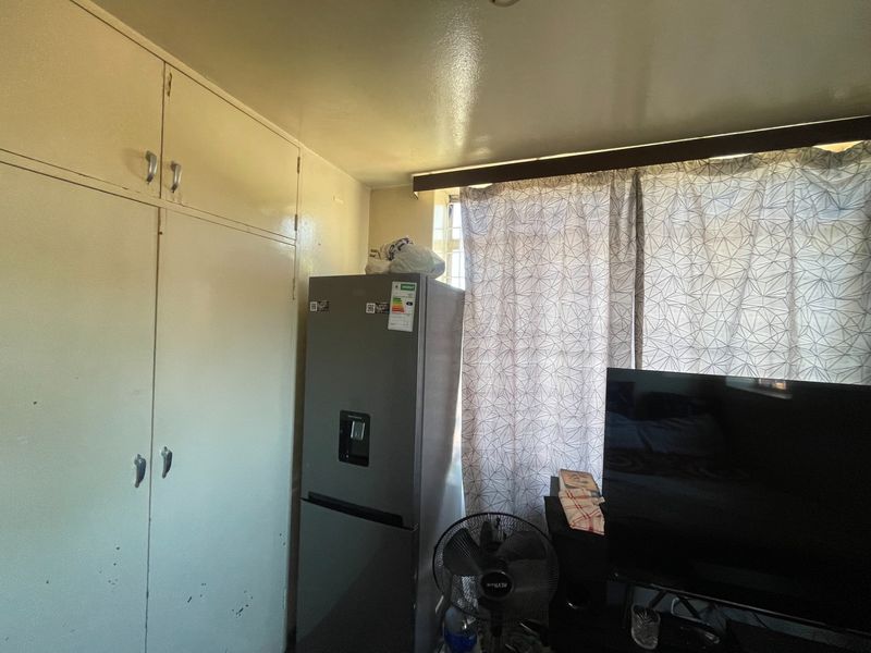A bedroom featuring built-in storage cupboards with visible wear and tear on the cabinet doors.