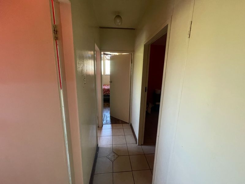 A functional hallway with tiled flooring providing access to multiple rooms within the apartment.