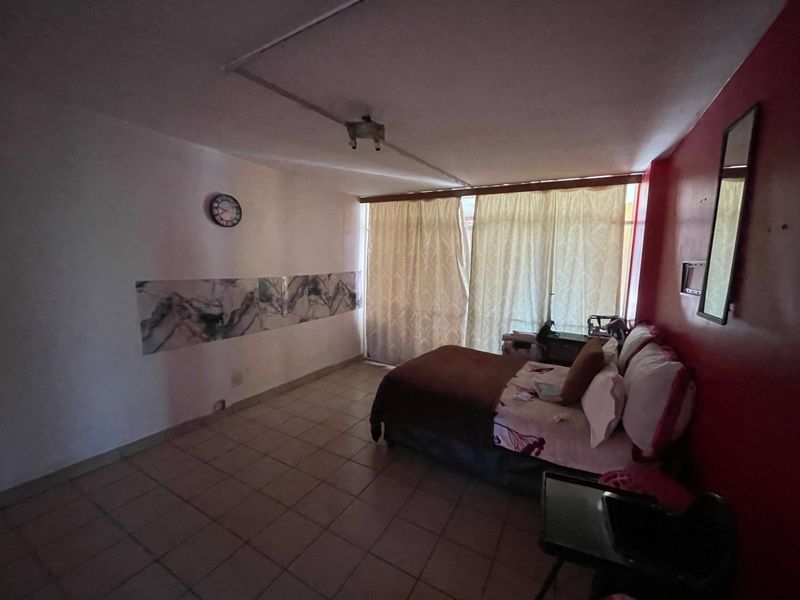 A bedroom featuring tiled flooring and access to a balcony through sliding glass doors, currently requiring cosmetic updates to the walls and ceiling.