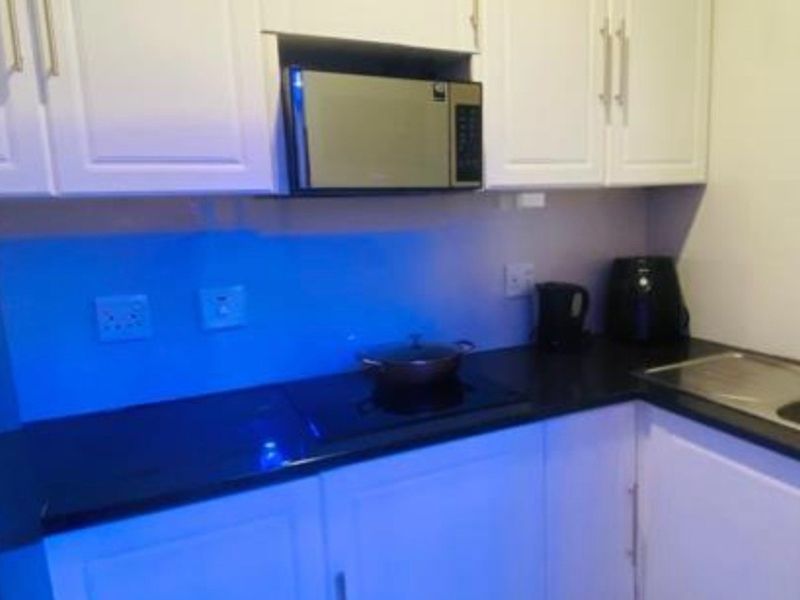 A compact kitchen featuring white cabinetry, black countertops, an integrated microwave, and an electric cooktop.