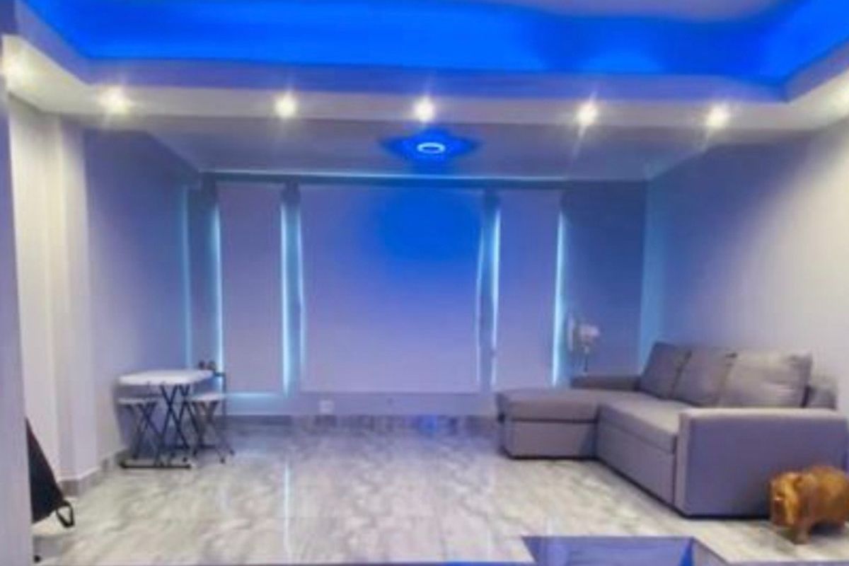 Living room featuring a raised platform area, tiled flooring, and modern recessed ceiling lighting with blue accent illumination.