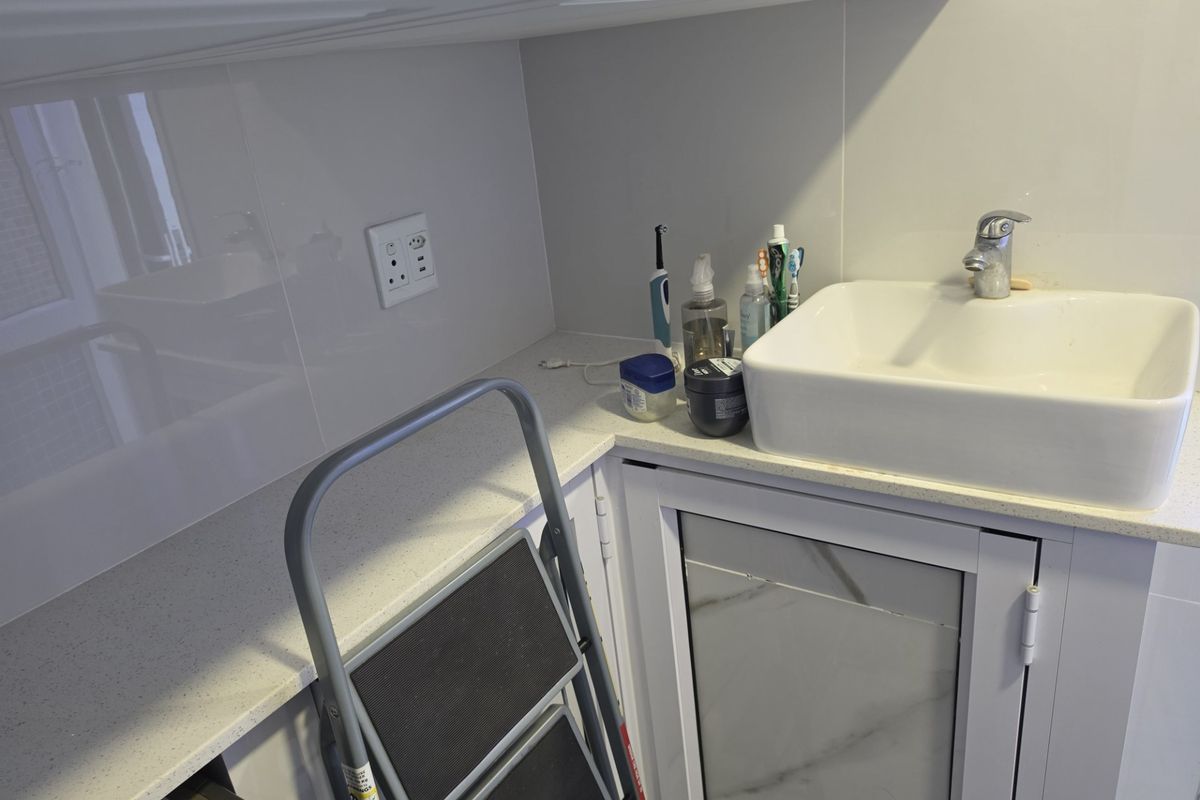 A compact bathroom vanity area featuring a modern basin, stone-look countertop, and white cabinetry with a clean splashback finish.