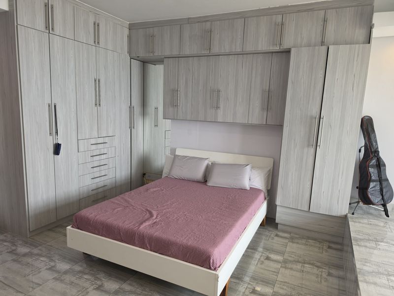 A well-appointed bedroom featuring extensive built-in cabinetry and overhead storage units, complemented by modern tiled flooring.