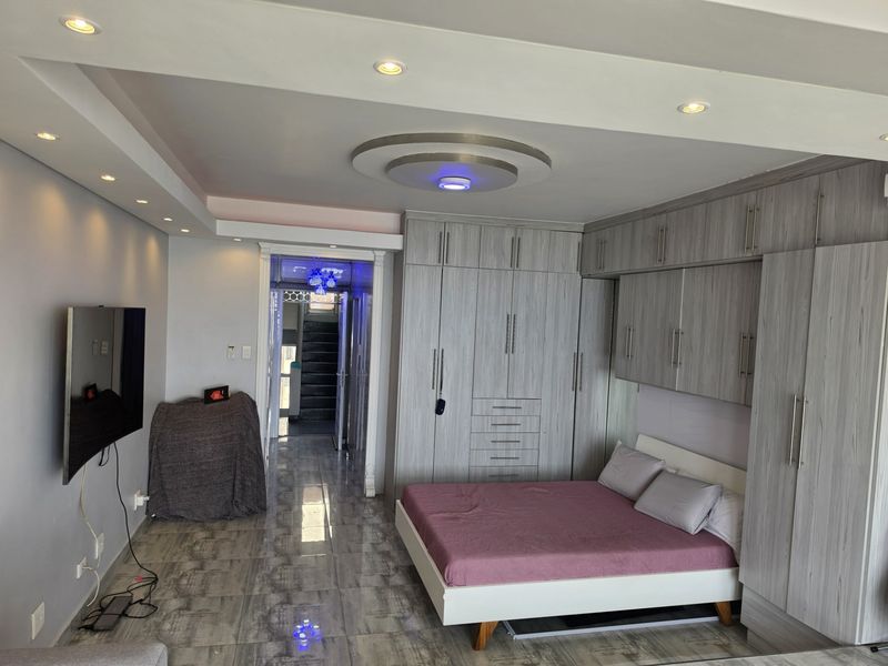 A well-maintained bedroom featuring extensive built-in cabinetry, modern recessed ceiling lighting, and polished tiled flooring.