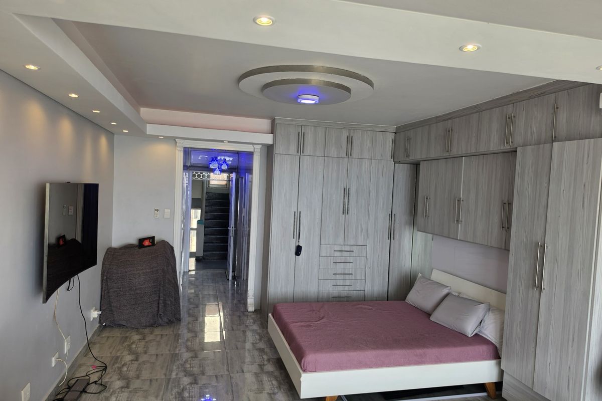 A well-maintained bedroom featuring extensive built-in cabinetry, modern recessed ceiling lighting, and polished tiled flooring.