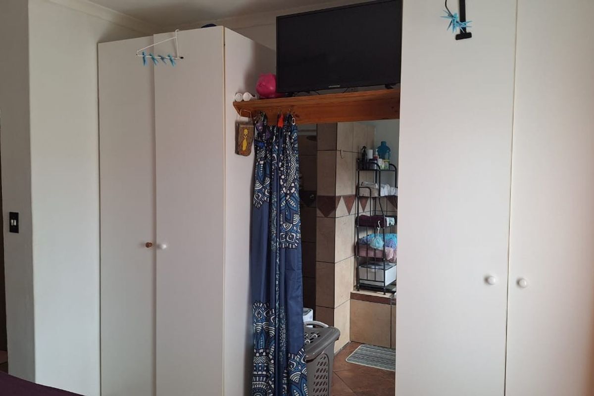 Bedroom featuring white built-in cupboards with integrated shelving and access to an adjoining bathroom area.