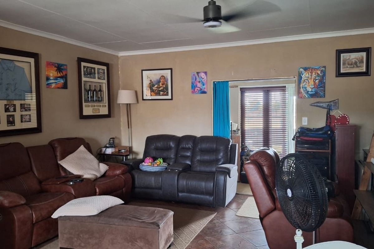 A comfortable living room featuring tiled flooring, a ceiling fan, and direct access to an outdoor area through a sliding glass door.