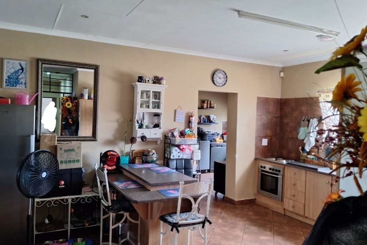 A functional kitchen featuring tiled flooring, built-in cabinetry, and an integrated oven, with an adjacent scullery area for additional storage and preparation space.