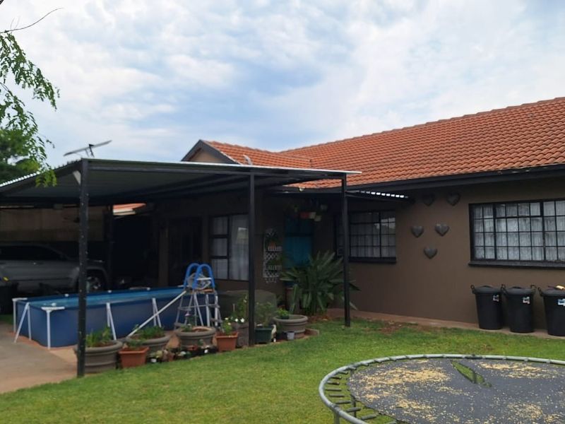 Rear view of the townhouse featuring a covered patio area, terracotta tiled roof, and a private garden space.
