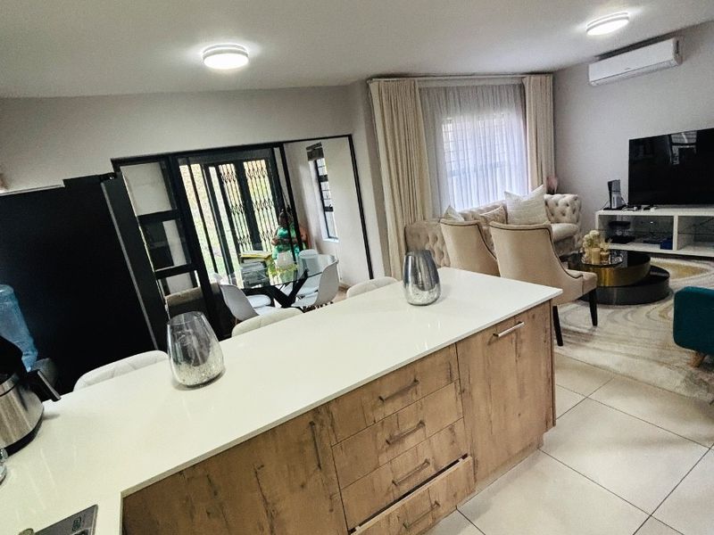 Open-plan living area featuring a modern kitchen island with wood-finish cabinetry, tiled flooring, and an integrated air conditioning unit.