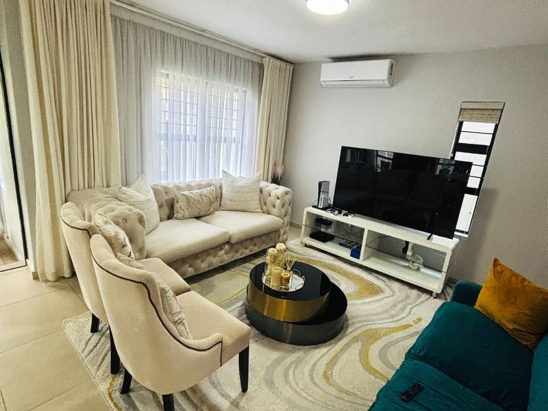 A well-maintained living room featuring tiled flooring, a wall-mounted split-system air conditioner, and neutral finishes, providing a comfortable and functional space.