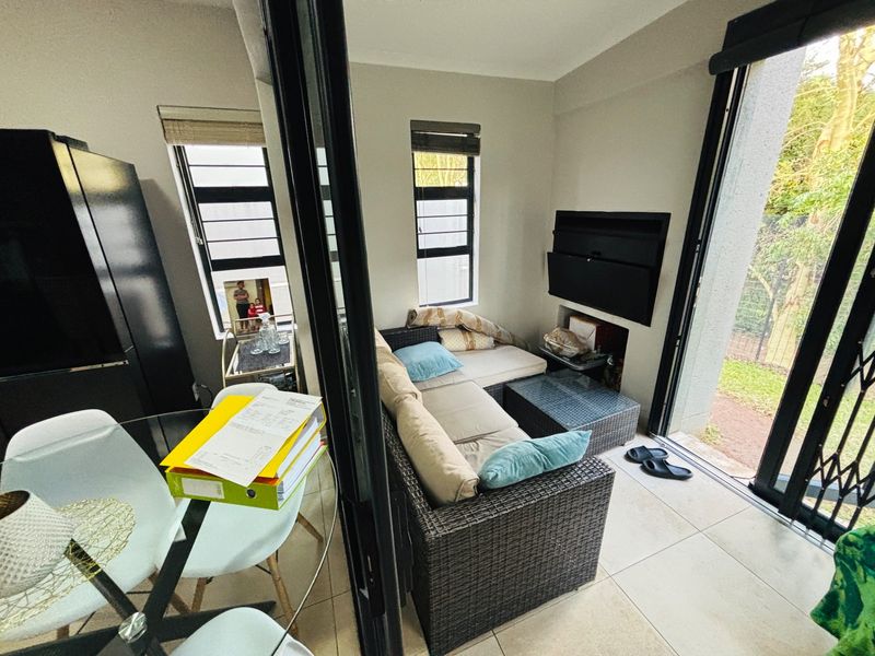 Open plan living area featuring tiled flooring, a built-in fireplace, and large sliding glass doors providing seamless access to the outdoor space.