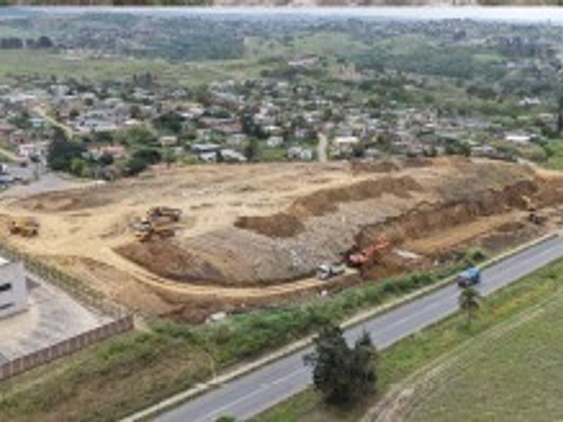 Aerial view of a large industrial development site featuring ongoing earthworks, adjacent to a main road and existing industrial infrastructure.