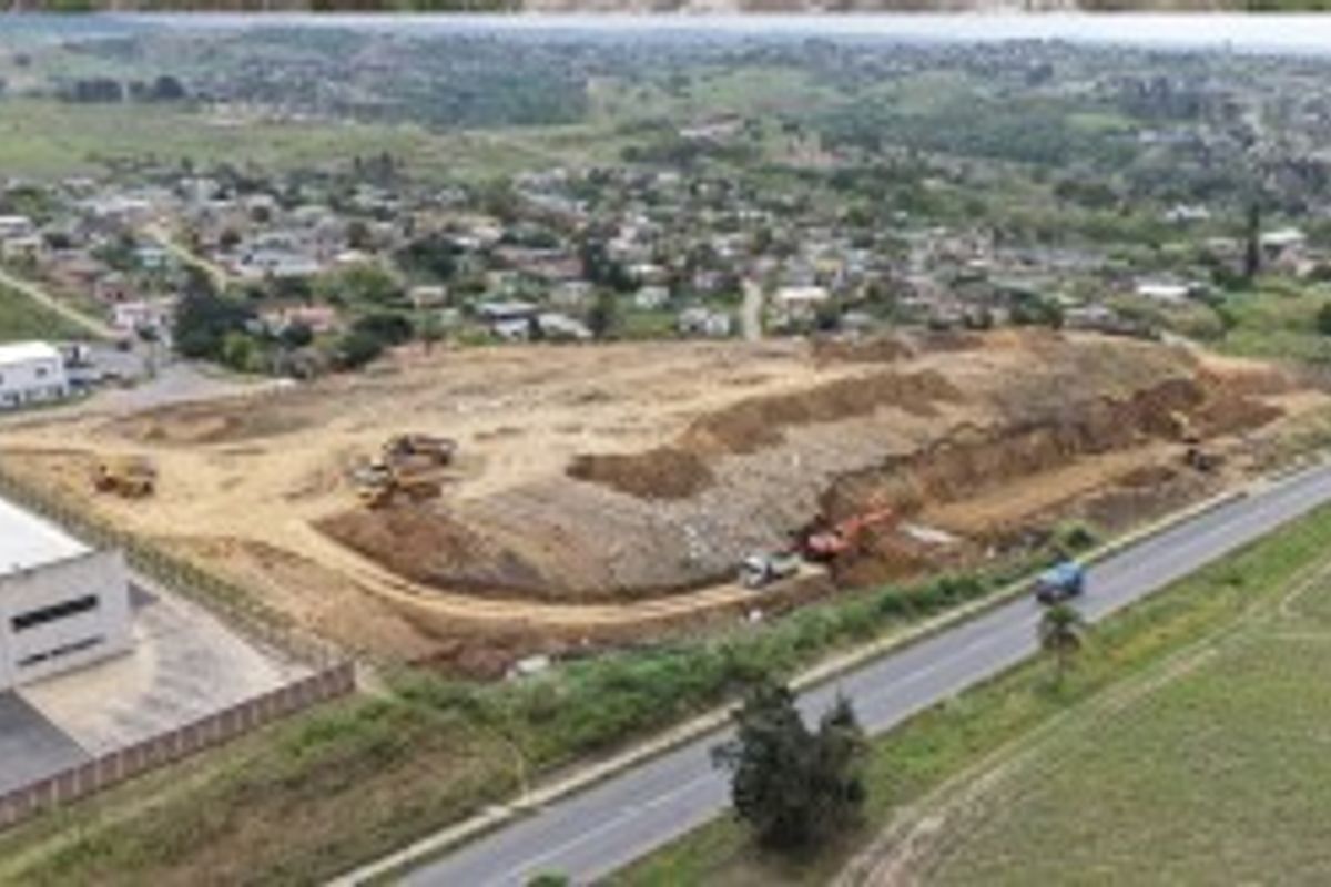 Aerial view of a large industrial development site featuring ongoing earthworks, adjacent to a main road and existing industrial infrastructure.