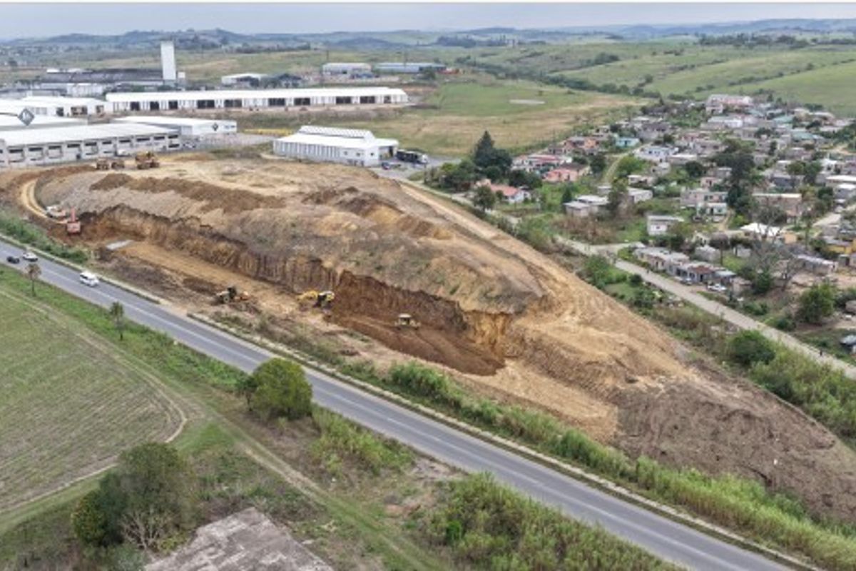 Aerial view of an industrial development site showing ongoing earthworks and excavation near a main road and surrounding residential area.