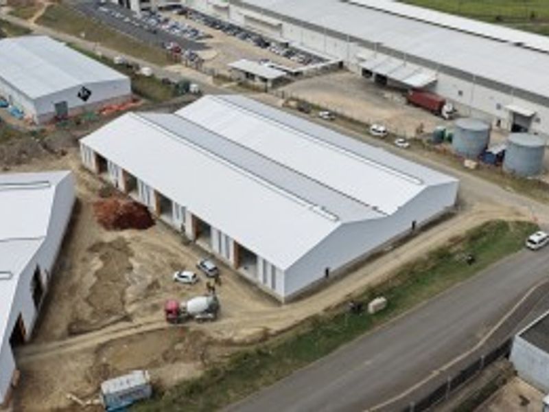 Aerial view of an industrial warehouse complex under development, featuring metal roofing and surrounding site access roads.
