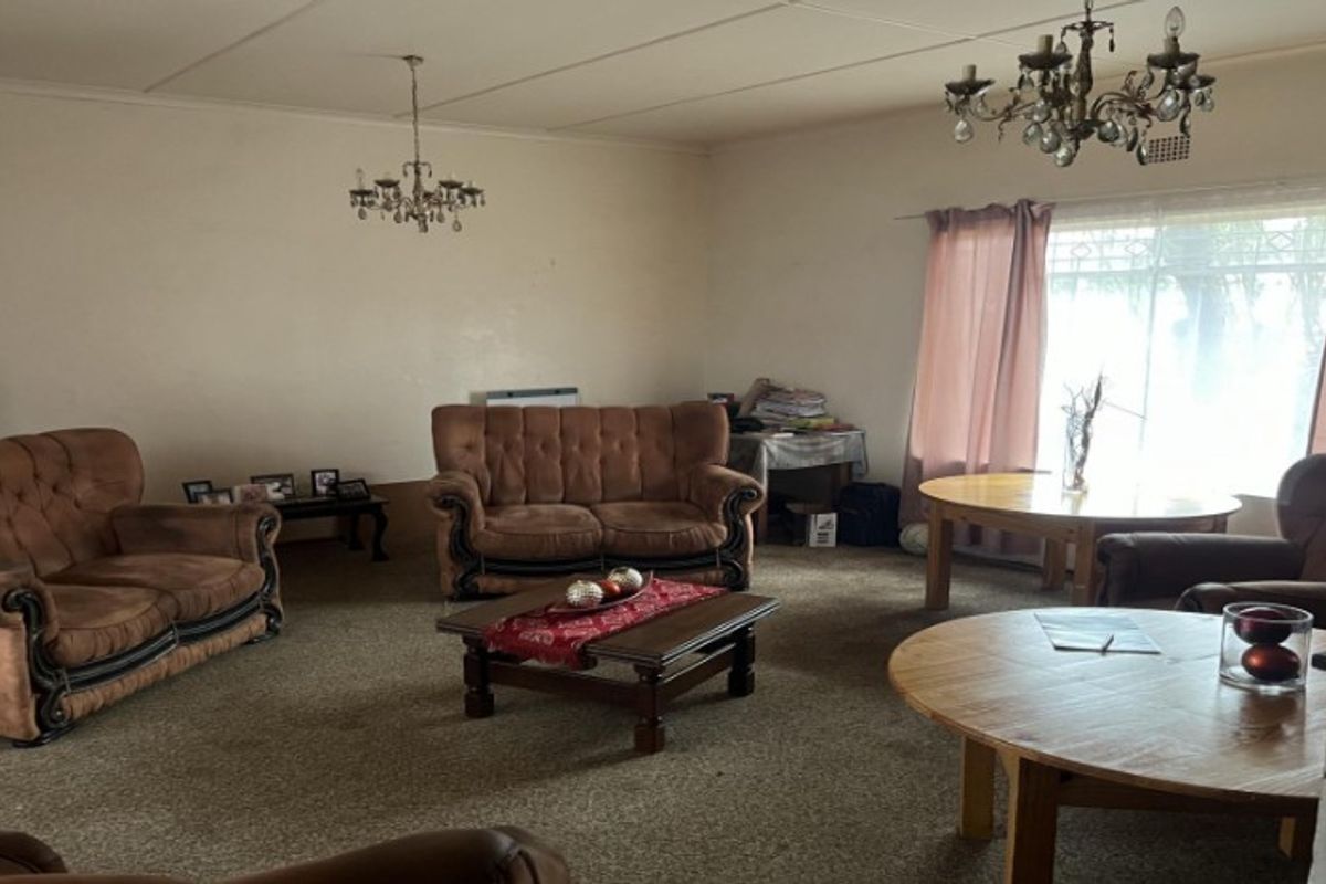 Spacious living room featuring carpet flooring, large windows for natural light, and traditional ceiling light fixtures, offering a blank canvas for modernization.