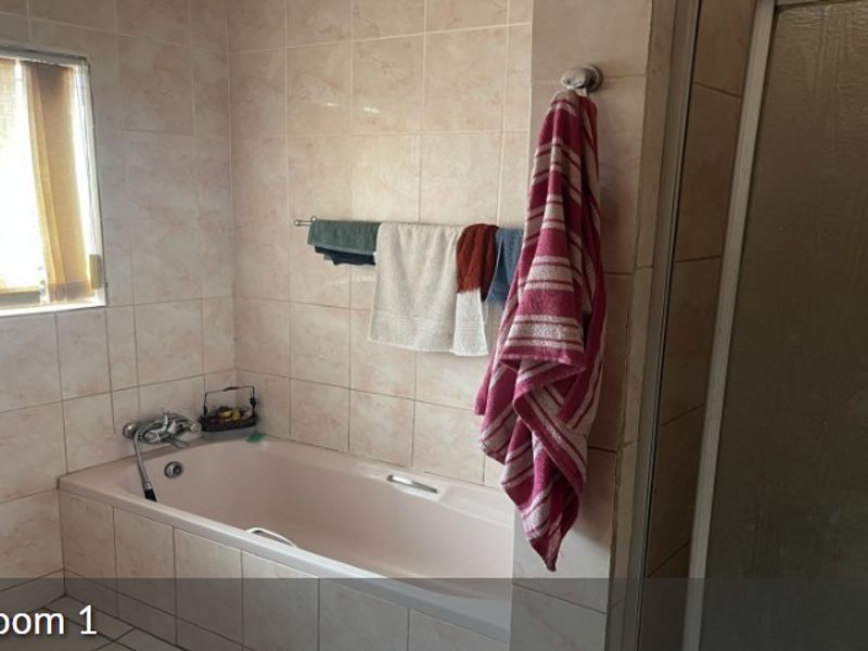 A functional bathroom featuring a built-in bathtub, tiled wall finishes, and a separate shower enclosure.