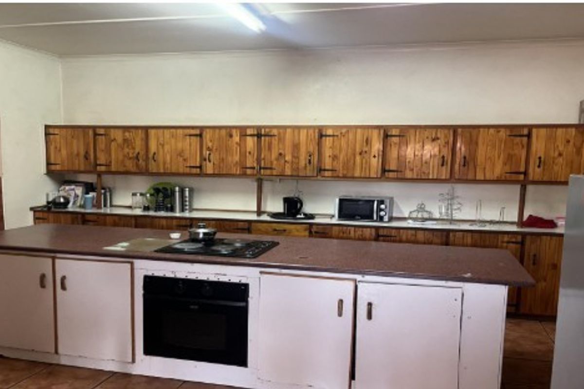 A functional kitchen featuring extensive wooden cabinetry, a central island with a built-in oven and cooktop, and tiled flooring throughout.