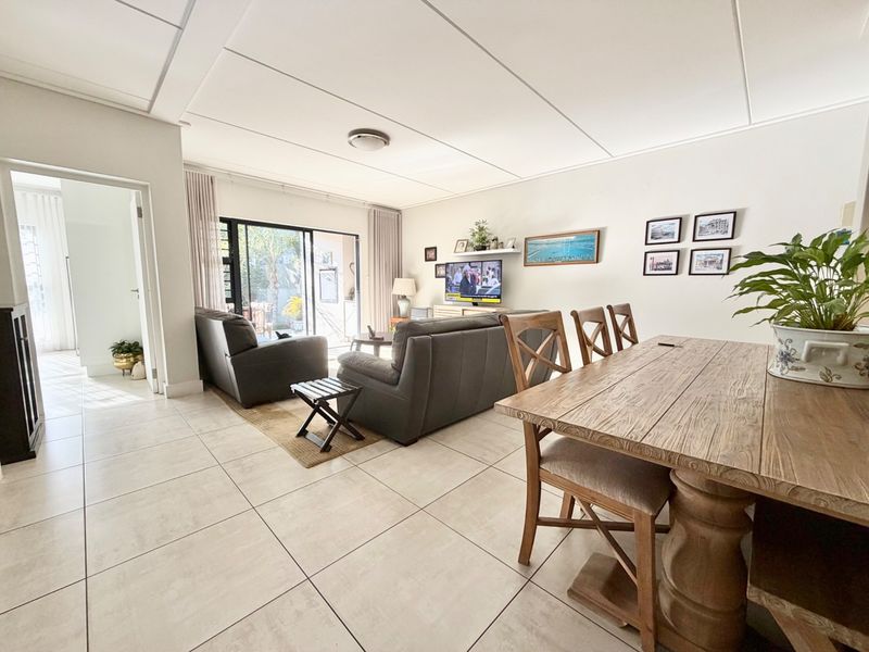 Spacious open-plan living and dining area featuring neutral tiled flooring, modern ceiling panels, and large sliding glass doors leading to an outdoor patio.