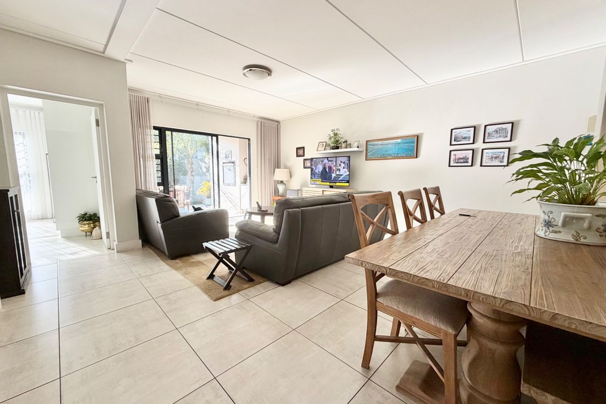 Spacious open-plan living and dining area featuring neutral tiled flooring, modern ceiling panels, and large sliding glass doors leading to an outdoor patio.