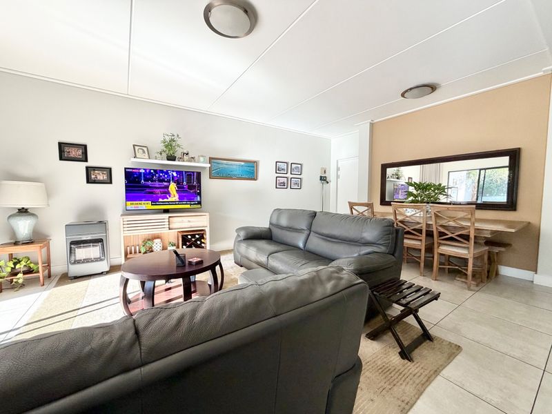 Open plan living and dining area featuring neutral wall tones, tiled flooring, and a dedicated accent wall, providing a functional and versatile living space.
