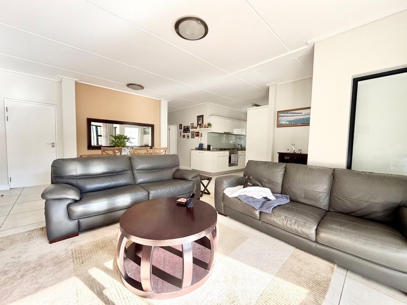 Spacious open-plan living area featuring tiled flooring and a functional kitchen with built-in cabinetry, oven, and hob, creating a comfortable and connected living space.