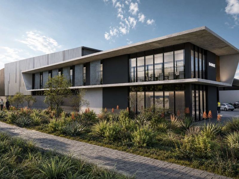 Modern commercial building exterior featuring a concrete facade, large glass windows, and a well-maintained landscaped garden with a paved walkway.