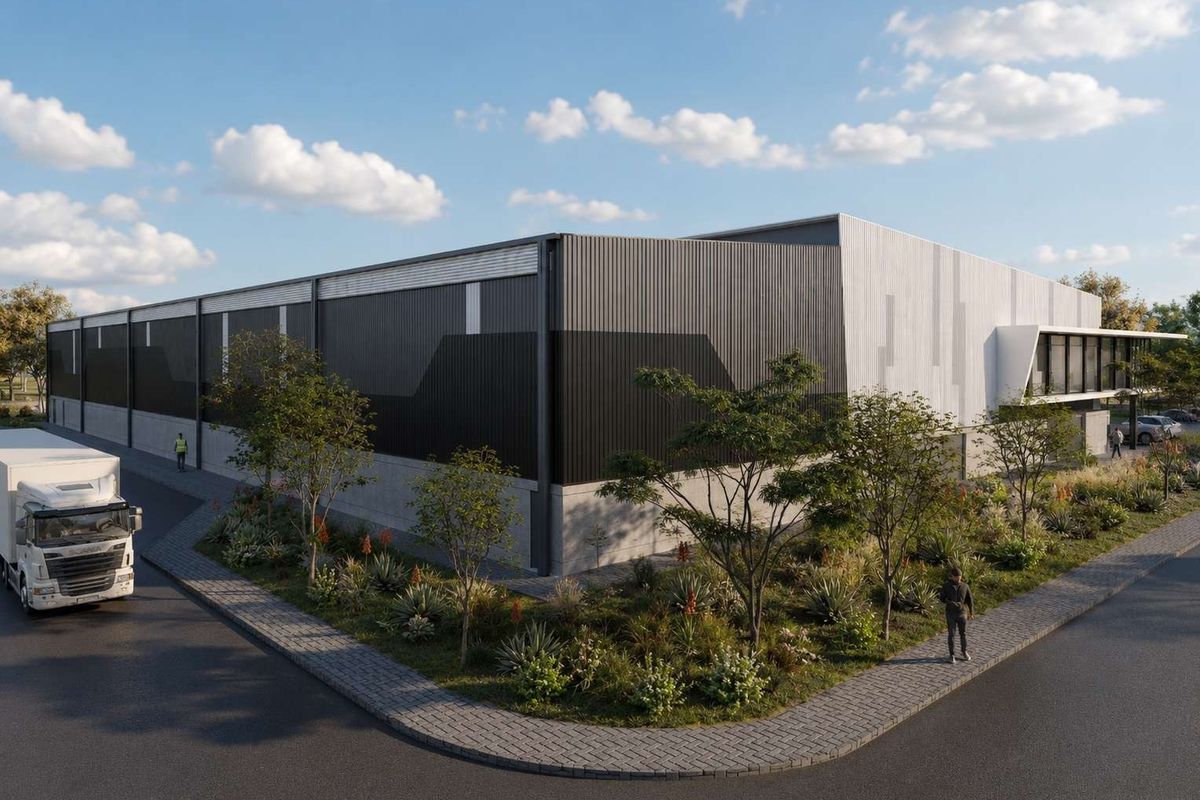 A modern industrial warehouse facility featuring contemporary metal cladding, concrete base, and landscaped surroundings with paved access.