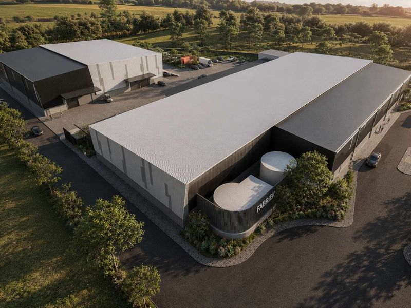 Aerial view of a modern industrial warehouse complex featuring multiple buildings, paved parking, and landscaped grounds in a rural setting.