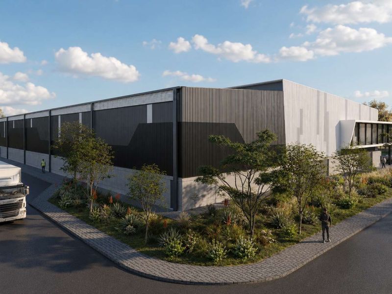 A modern industrial warehouse facility featuring contemporary metal cladding, concrete base, and landscaped surroundings with paved access.