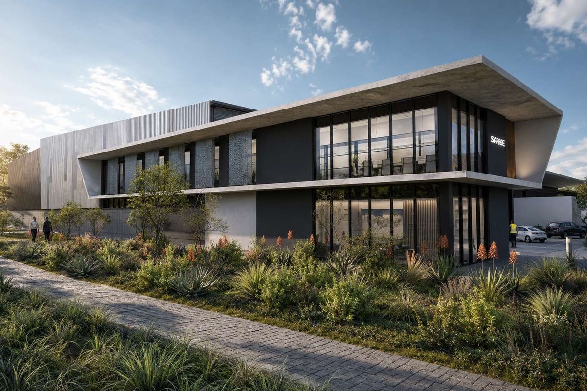 Modern commercial building exterior featuring a concrete facade, large glass windows, and a well-maintained landscaped garden with a paved walkway.