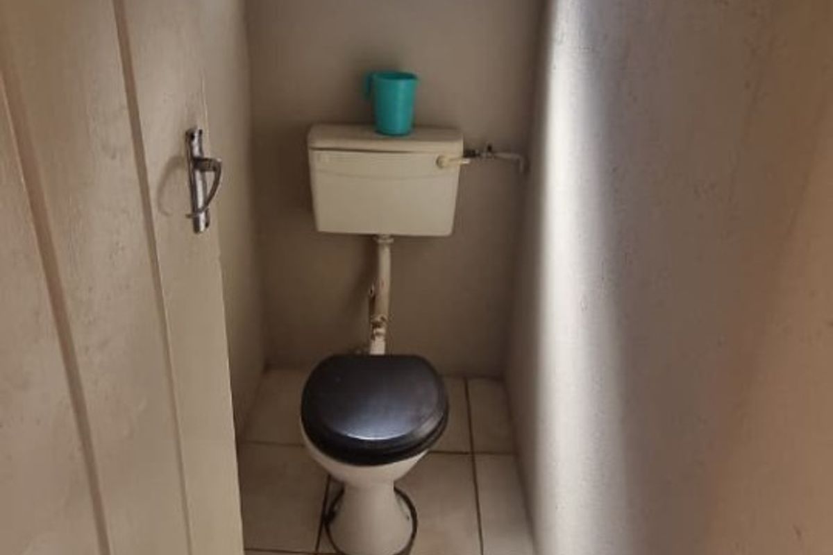 A compact, functional guest toilet featuring tiled flooring, a standard cistern toilet, and a small obscured glass window for natural light and ventilation.