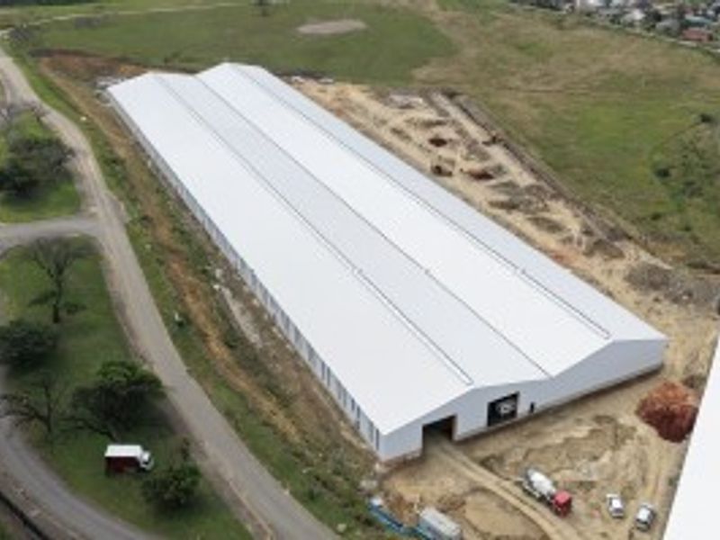 Aerial view of a large industrial warehouse facility featuring a modern metal roof and surrounding site development in progress.
