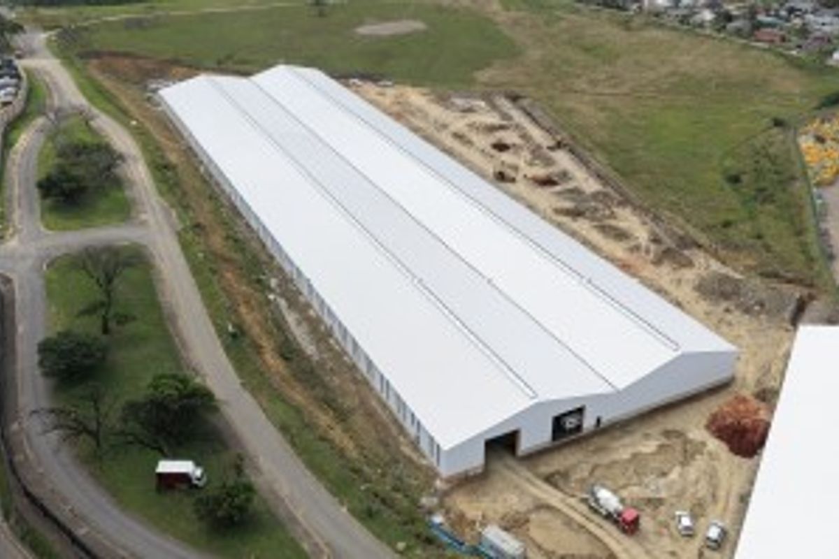 Aerial view of a large industrial warehouse facility featuring a modern metal roof and surrounding site development in progress.