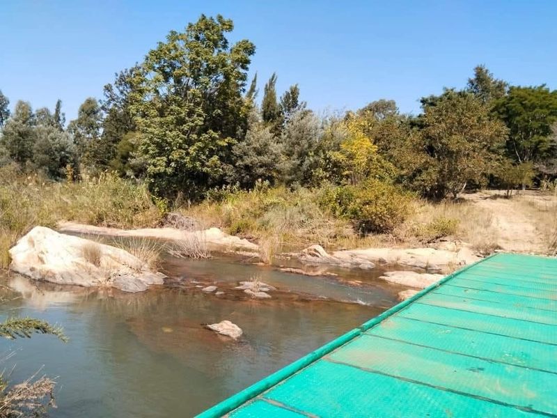 A scenic view of a natural river flowing through the farm property, featuring rock formations and surrounding native vegetation.
