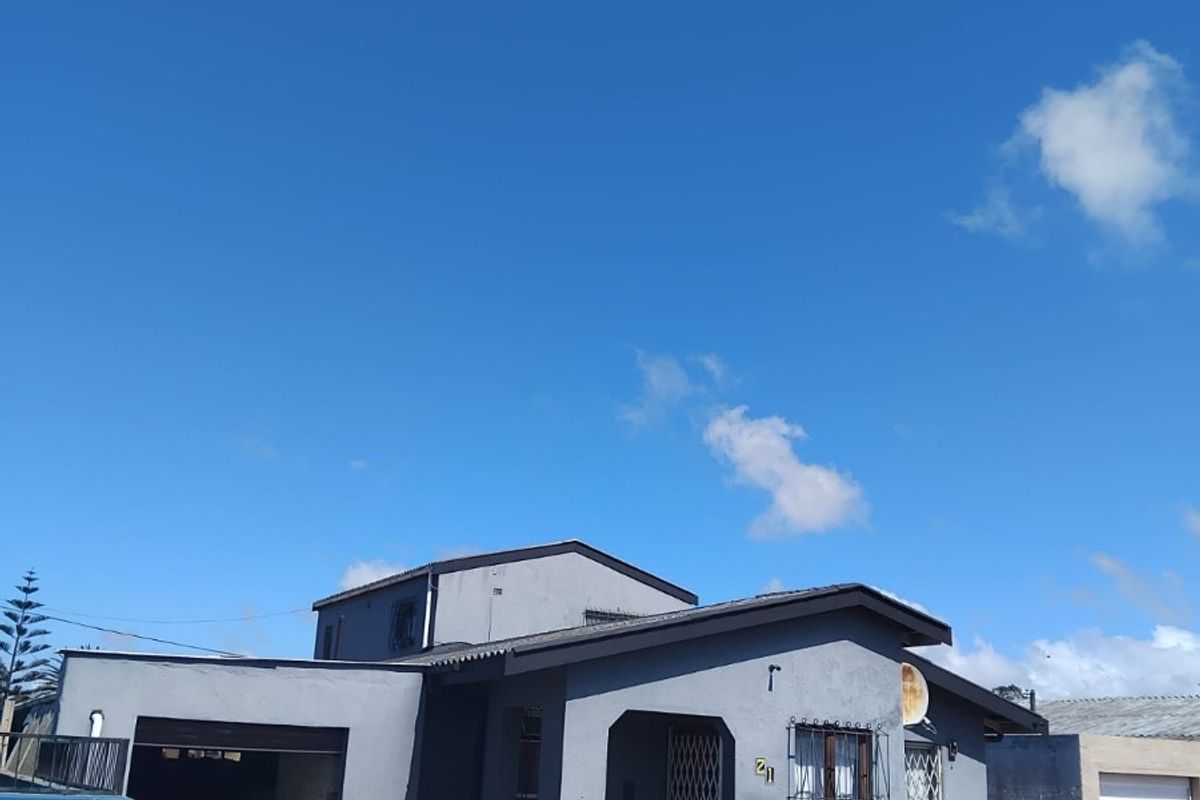 Front elevation of a single-story house featuring a paved driveway, single garage, and perimeter wall with security gates.