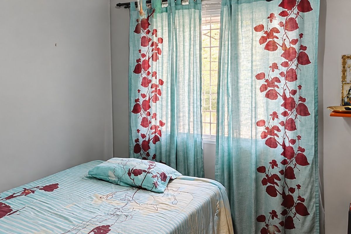 A functional bedroom featuring a window with curtain rod and neutral wall finishes.